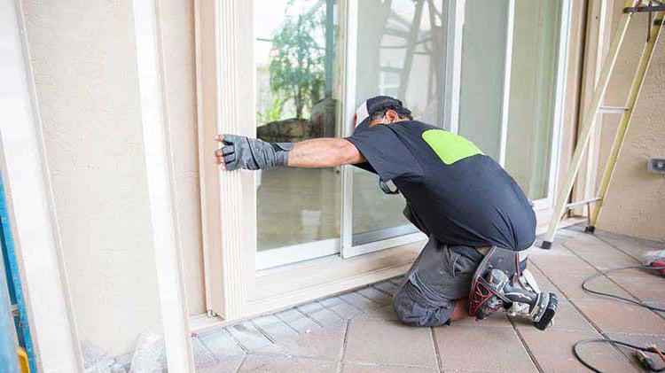 Man preparing sliding glass doors for a storm.