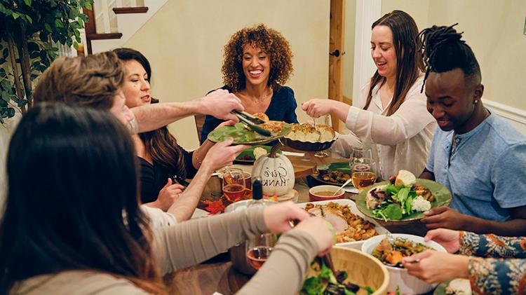 Friends enjoying a Thanksgiving meal, with different multicultural dishes.